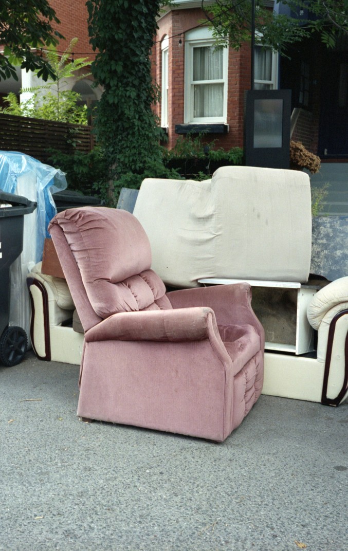 A sofa and mattress being loaded into a junk removal trailer